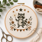 Sparkler Raccoon Mini cross stitch pattern stitched in a hoop mockup by Calico & Clove