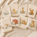 Meadow Baby machine embroidery design bundle showing all eight baby animal designs on cream nursery textiles